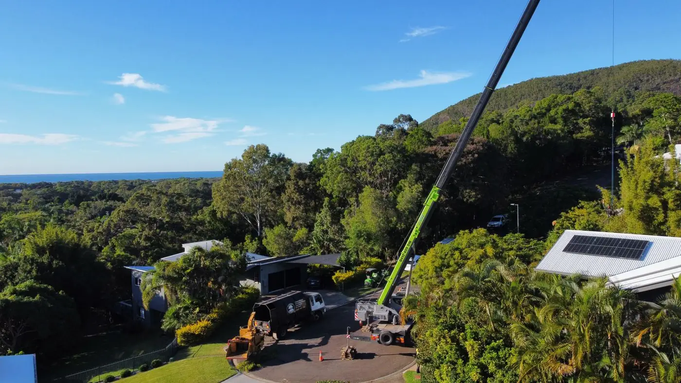 Summit Tree Services crane working above homes on the Sunshine Coast